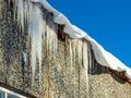 Icicles hanging from rooftop covered with a lot of snow Royalty Free Stock Photo