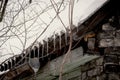 Icicles hanging from the snow-covered roof of an aged dark brick house Royalty Free Stock Photo