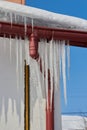 Icicles on plastic drainage pipes,roof with snow and hanging icicles