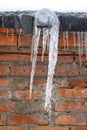 Icicles on the roof against a background of red brick brick wall Royalty Free Stock Photo