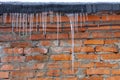 Icicles on the roof against a background of red brick brick wall Royalty Free Stock Photo