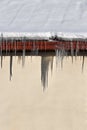 Icicles on the roof of the house, natural shade on beige wall, copy space. A lot of snow on the roof Royalty Free Stock Photo
