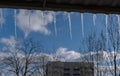 Icicles shimmering in the sun hanging from the roof against a blurred background of the cityscape.