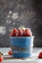 Icing sugar fly on beautiful red strawberry in blue pot. Strawberries on black background Royalty Free Stock Photo