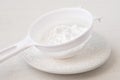 Icing sugar in a plastic sieve on top of white ceramic plate Royalty Free Stock Photo