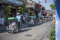 Ickshaw riders carry Chinese tourists on a tour in the streets of Hoi An, Vietnam