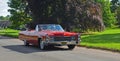 Classic Red Cadillac Eldorado convertible being driveh though village. Royalty Free Stock Photo