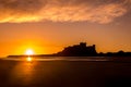 The iconic Bamburgh Castle at sunrise, with the nearby beach deserted.