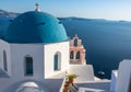 Iconic blue-domed church with pink bell tower and the Aegean Seain Greece Royalty Free Stock Photo