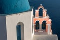 Iconic blue-domed church with pink bell tower and the Aegean Seain Greece Royalty Free Stock Photo
