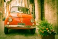 Iconic Italian car in grungy narrow street in small town.