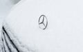 Iconic Mercedes-Benz logotype insignia covered with snow