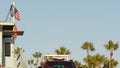 Iconic retro wooden lifeguard watch tower and baywatch red car. Life buoy, american state flag and palm trees against blue sky. Royalty Free Stock Photo