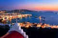 Beautiful view Mykonos, Greece after sunset, Greek Orthodox church, ships, whitewashed houses. Town lights up. Vacations Royalty Free Stock Photo