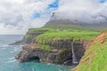 The iconic waterfall of Gasadalur on faroe islands and the remote village in the background