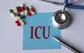 ICU - medical abbreviation on a blue sheet on the background of tablets, stethoscope and pen