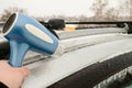 Icy car body and a door that cannot be opened after freezing rain. Warming up using hairdryer. Royalty Free Stock Photo