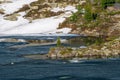 Icy lake surrounded by rocky snow covered forestry. Spring lake high in the mountains, green spruce on the cape surrounded by ice Royalty Free Stock Photo