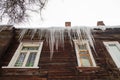 Icy, large icicles hang on the edge of the roof, winter or spring. Royalty Free Stock Photo