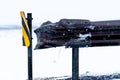 Icy traffic barrier with a yellow and black road sign Royalty Free Stock Photo