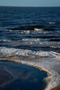 Icy winter beach near the sea with frozen sand and ice blocks in the water. Cold dunes Royalty Free Stock Photo