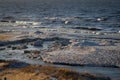 Icy winter beach near the sea with frozen sand and ice blocks in the water. Cold dunes Royalty Free Stock Photo