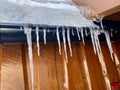 Icycles hanging from guttering on the side of a wooden house. Hovden, Norway, Feb 2023.