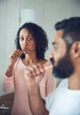 Id love to know what hes thinking. a mature woman looking at her husband while brushing their teeth in the bathroom. Royalty Free Stock Photo