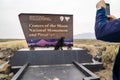 Pet owner photographs his black labrador retriever dog at Craters of the Moon National Monument sign