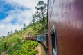 IDALGASHINNA, SRI LANKA - JULY 16, 2016: Local train rides near Idalgashinna village. Locals hang out of door