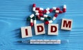 IDDM - acronym on wooden cubes on a blue background with tablets and thermometer