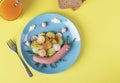 Idea breakfast for kids - funny snail from sausage with cucumber and radishes salad on a plate, Top view