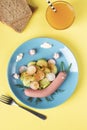 Idea breakfast for kids - funny snail from sausage with cucumber and radishes salad on a blue plate, Top view