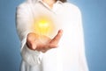 Idea concept. Businesswoman demonstrating glowing light bulb illustration on blue background, closeup