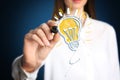 Idea concept. Businesswoman drawing glowing light bulb illustration on virtual screen Royalty Free Stock Photo