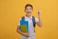 Idea Concept. Excited schoolboy with backpack and notebooks pointing upwards with pencil Royalty Free Stock Photo