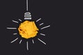 Idea concept with lightbulb made out of yellow crumbled paper ball and drawn white lines on black background Royalty Free Stock Photo