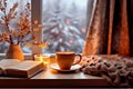 idea of coziness, hygge, home comfort. Snowy forest outside window. Coffee, scarf and book on background of winter evening