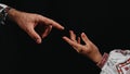 Idea of earth creation. Ukrainian hands reaching out, pointing finger together on black background. Man and woman in