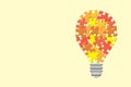 Idea lightbulb made of orange jigsaw pieces against a yellow background