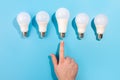 Idea male hand touch big LED light bulbs on blue color background. Flat lay with copy space Royalty Free Stock Photo