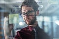 Idea mining. a young businessman brainstorming with sticky notes on a glass wall in a modern office. Royalty Free Stock Photo