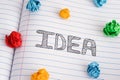 Idea word on notebook sheet with some colorful crumpled paper balls on it Royalty Free Stock Photo