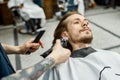 Ideal beard shape. Barber with tattoo on his arm holding hair clipper and trimming beard of his client. Barbershop Royalty Free Stock Photo