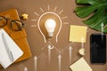 Ideas inspiration concepts with lightbulb, modern smartphone, pen, monstera leaves, eyeglasses and notebook