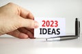 2023 Ideas symbol. White paper with words 2023 Ideas. Businessman hand. Metallic pen. Beautiful white table white background.