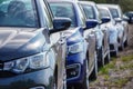 Identical blue cars stand in a row in a Parking lot or market for sale. View of the side mirrors, the Dealership. New car sales.