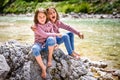 Identical twin girls sitting on river rock after nature hiking