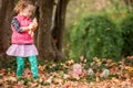Identical twins having fun with autumn leaves in the park, blond cute curly girls, happy kids, beautiful girls in pink jackets Royalty Free Stock Photo