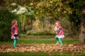 Identical twins having fun with toys and leaves in autumn in the park, blond cute curly girls, happy girls,beautiful girls in pink Royalty Free Stock Photo